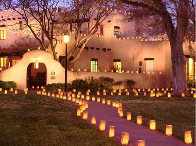 Pathway lit with glowing luminarias leading to a cozy adobe-style building.