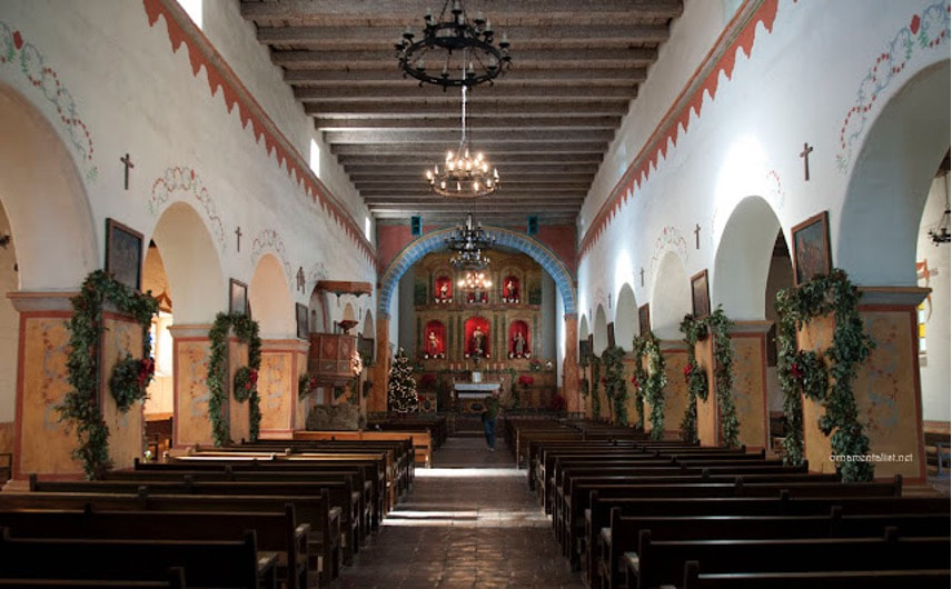 Interior of a historic church with wooden pews and ornate altar.