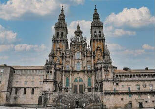 The ornate facade of a historic cathedral with twin towers under a blue sky.