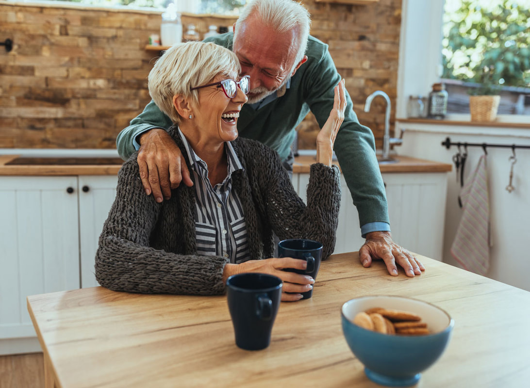 Elderly couple sharing a warm moment in a cozy kitchen.