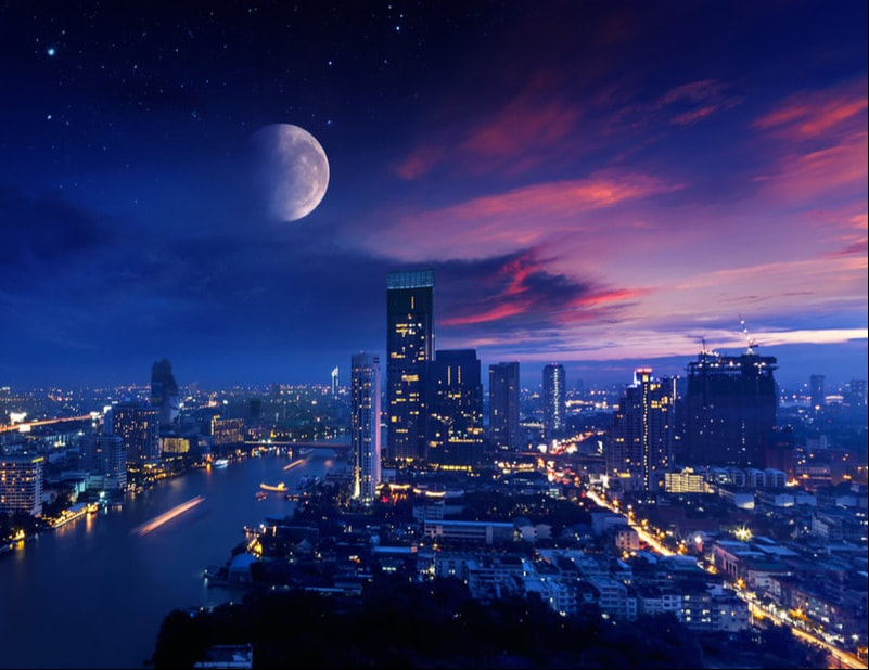 City skyline at dusk with a large moon above.