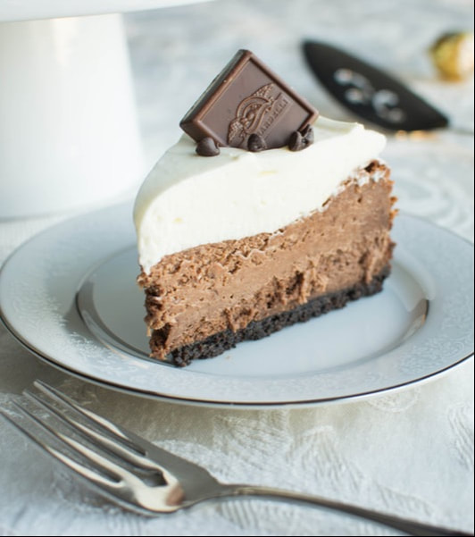 A slice of chocolate mousse cake topped with cream and a chocolate square.