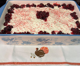 A dessert topped with whipped cream and berries in a glass dish.