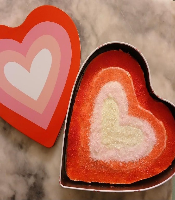 Heart-shaped box with colorful layered dessert inside.