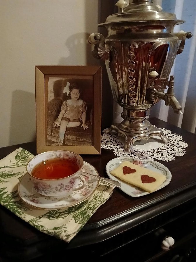 A vintage tea setup with a cup of tea, biscuits, and an old photograph.