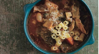 Hearty bowl of vegetable soup with pasta and herbs.