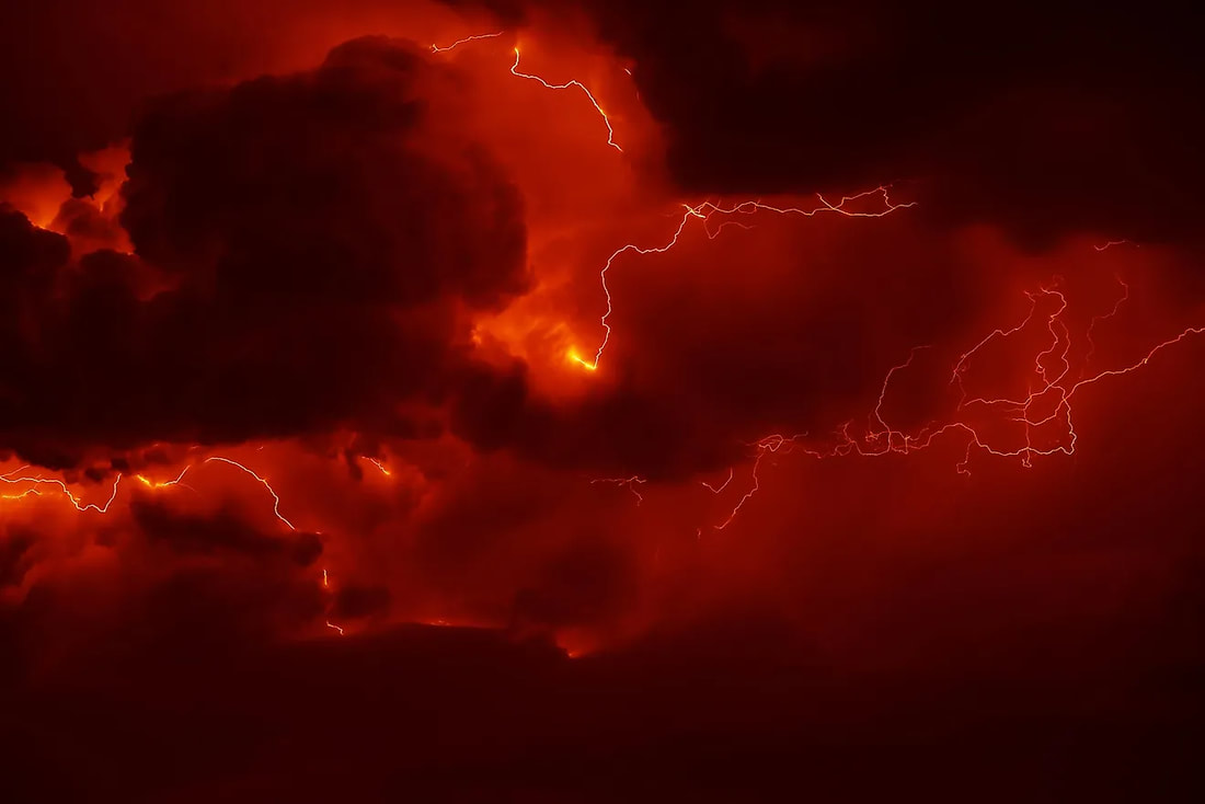 A dramatic red sky with lightning striking through dark clouds.