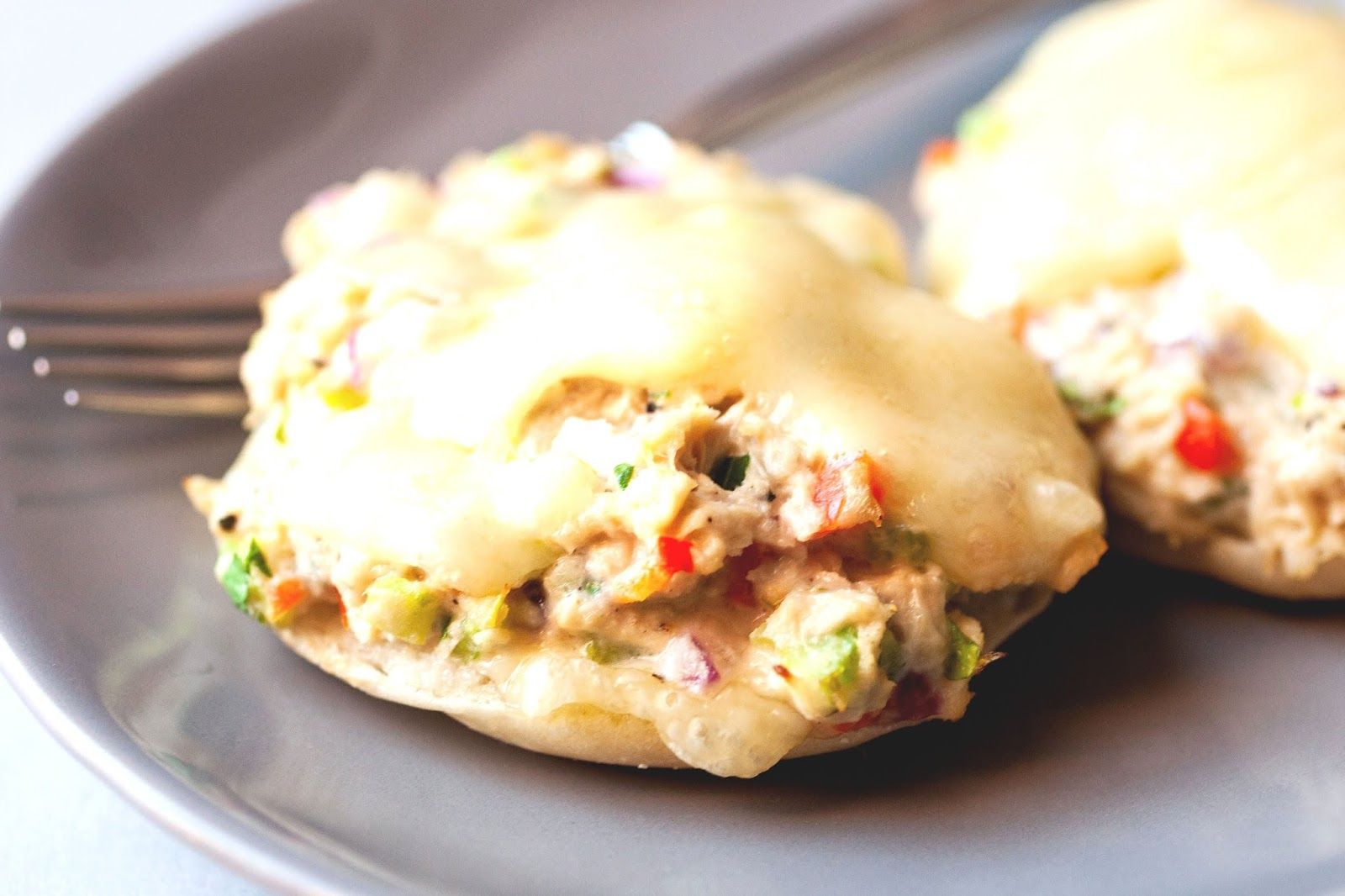 Open-faced sandwich with melted cheese and vegetables.