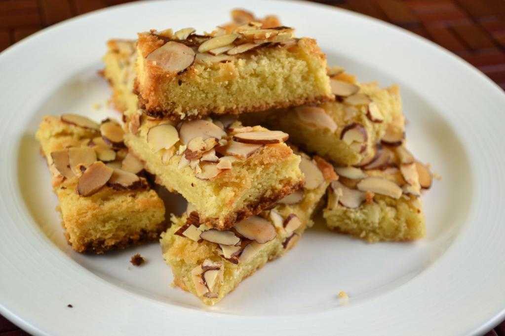 Almond-topped cake bars arranged on a white plate.