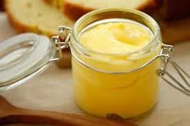A jar of creamy, yellow homemade butter on a wooden board.
