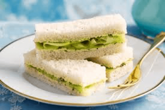 Stacked cucumber sandwiches with lettuce on a plate.