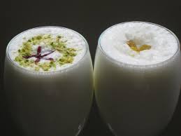 Two glasses of creamy Indian lassi garnished with pistachio and saffron.