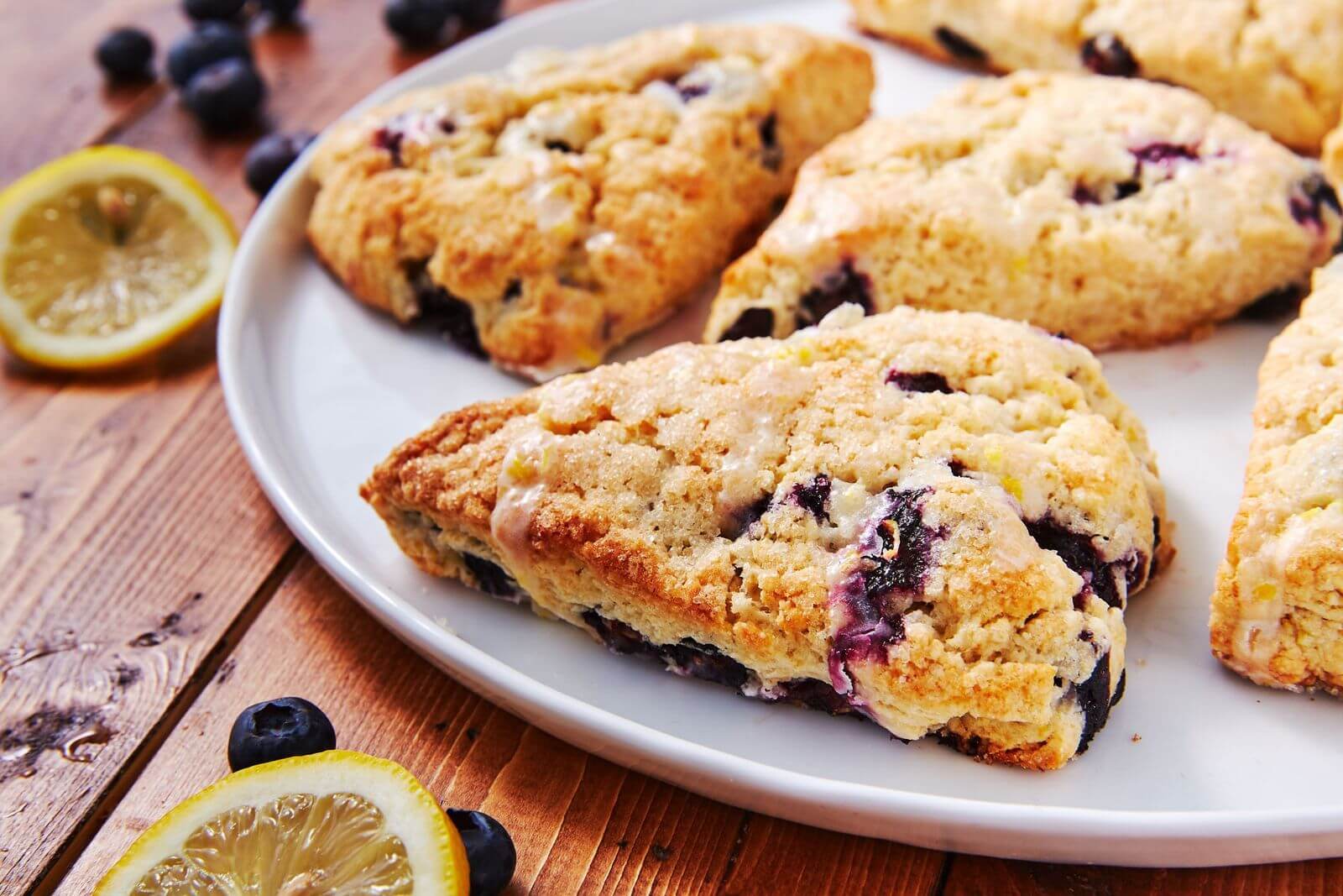 Close-up of freshly baked blueberry scones on a white plate.