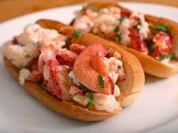 Two lobster rolls served in soft buns on a white plate.