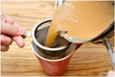 Pouring tea through a strainer into a cup.