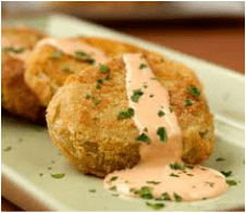 Golden crab cakes garnished with herbs and drizzled with creamy sauce.