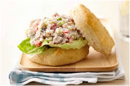 A chicken salad sandwich on a biscuit with lettuce.