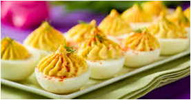 Deviled eggs topped with paprika and herbs on a plate.