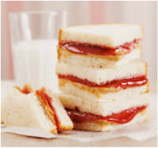 Stack of peanut butter and jelly sandwiches with a glass of milk.