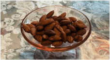 A glass bowl filled with roasted almonds.