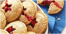 Freshly baked cherry pies with golden crusts on a blue surface.