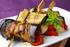 Grilled eggplant rolls stuffed with cheese and herbs on a plate.