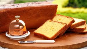 Slices of pound cake on a wooden board with a knife.
