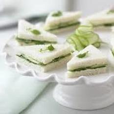 Elegant cucumber tea sandwiches on a white pedestal plate.