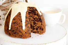 A slice of fruit cake with white icing on a plate.