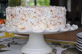 A coconut-covered cake on a white pedestal stand.