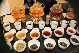 A tea tasting setup with various teas and infusions in bowls and teapots.