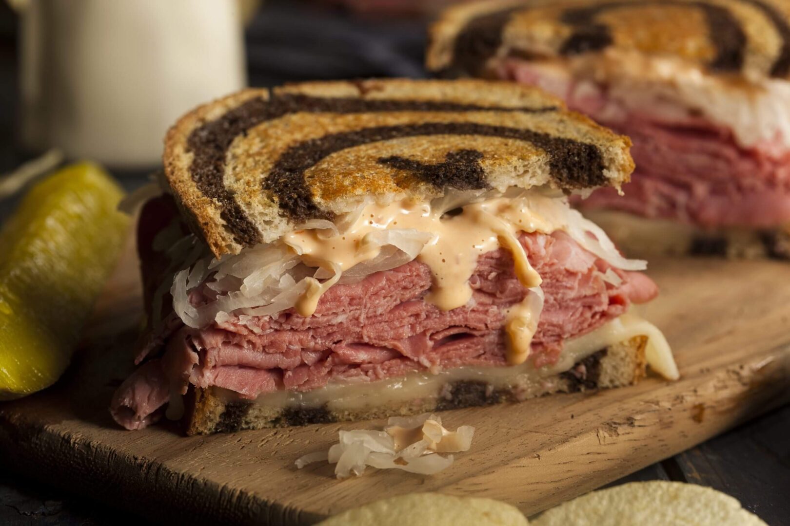 A close-up of a juicy Reuben sandwich with melted cheese and corned beef.