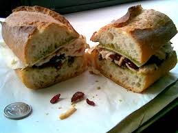 Sliced ciabatta sandwich with olives and pine nuts.