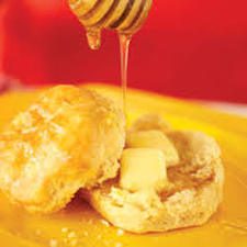 Honey dripping onto a buttered biscuit.
