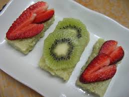 Three pieces of fruit-topped green cake on a white plate.