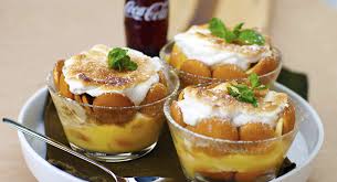 Two bowls of bread pudding topped with cream and mint leaves, with a Coca-Cola bottle in the background.