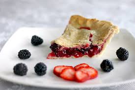 A slice of berry pie with fresh blackberries and sliced strawberries.