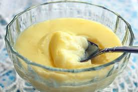 Creamy yellow custard in a glass bowl with a spoon.