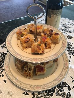 Two-tier plate stand with assorted baked scones topped with nuts and fruits.