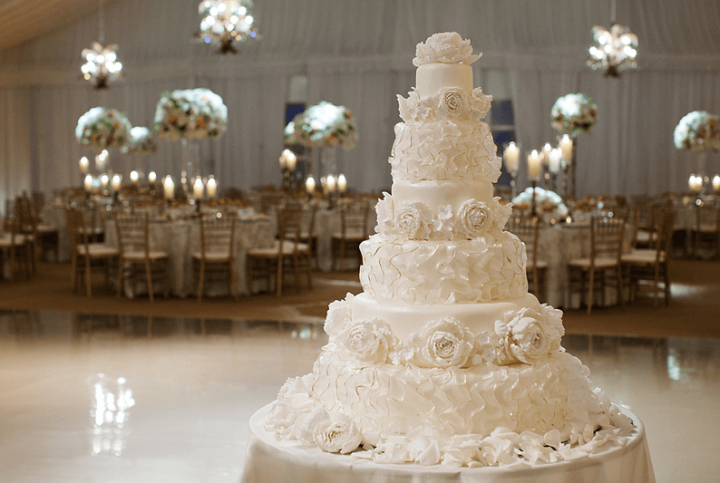 Elegant multi-tiered white wedding cake with intricate floral designs.