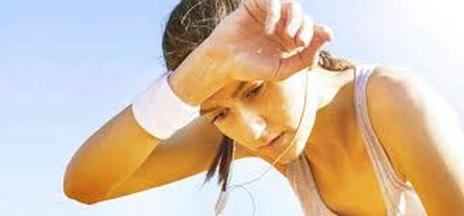 Woman wiping sweat from forehead during workout outdoors.