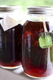 Two jars with dark liquid and tea bags inside, covered with cloth.