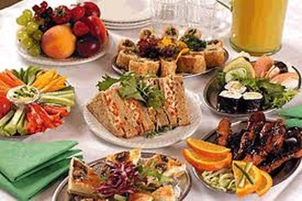 A variety of sandwiches, sushi, and fruit on a table.