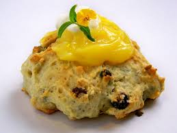 A scone topped with lemon curd and a mint leaf.