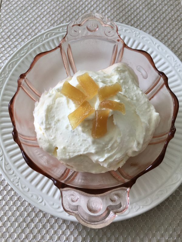 Whipped cream dessert topped with pineapple chunks in a pink glass bowl.