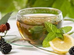 A glass cup of herbal tea with mint and lemon.