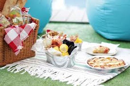 A picnic setup with a basket, cheese, and snacks on a blanket.