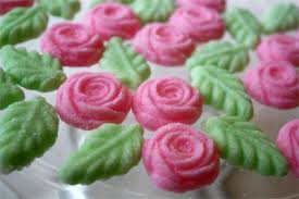Pink rose-shaped frosting decorations with green leaves on a cake.