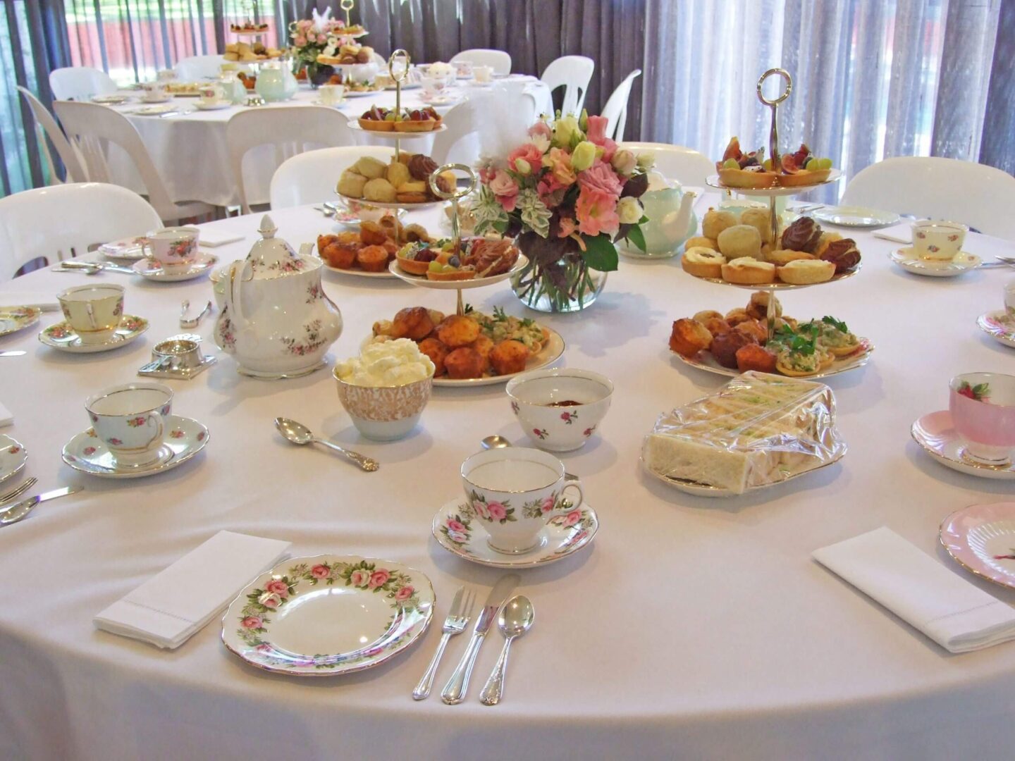 Elegant table set for afternoon tea with pastries and floral centerpiece.