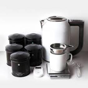 Electric kettle with tea jars and a cup on a scale.
